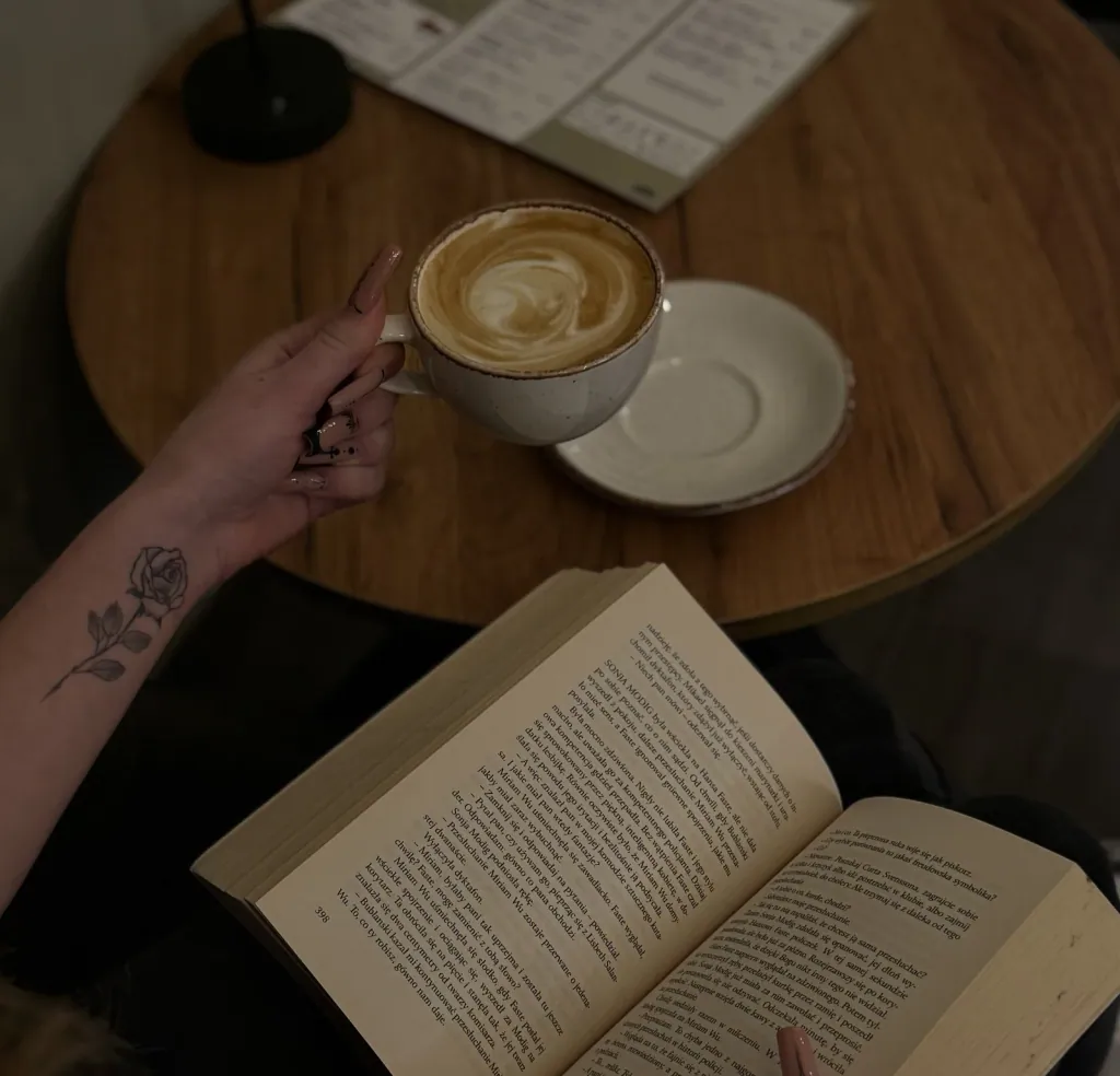 Filiżanka cappuccino i otwarta książka na drewnianym stoliku