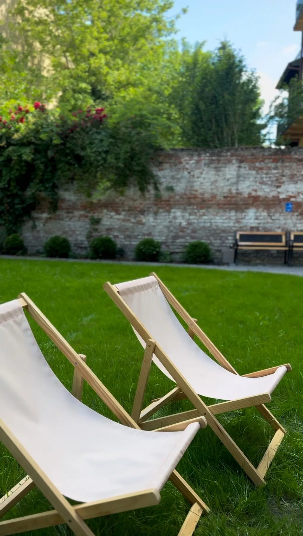Dwa drewniane leżaki na trawie w ogrodzie Siesta Cafe