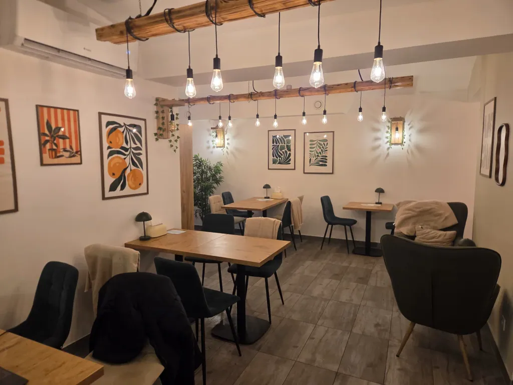 Sala Siesta Cafe — drewniane stoliki i rząd żarówek pod sufitem